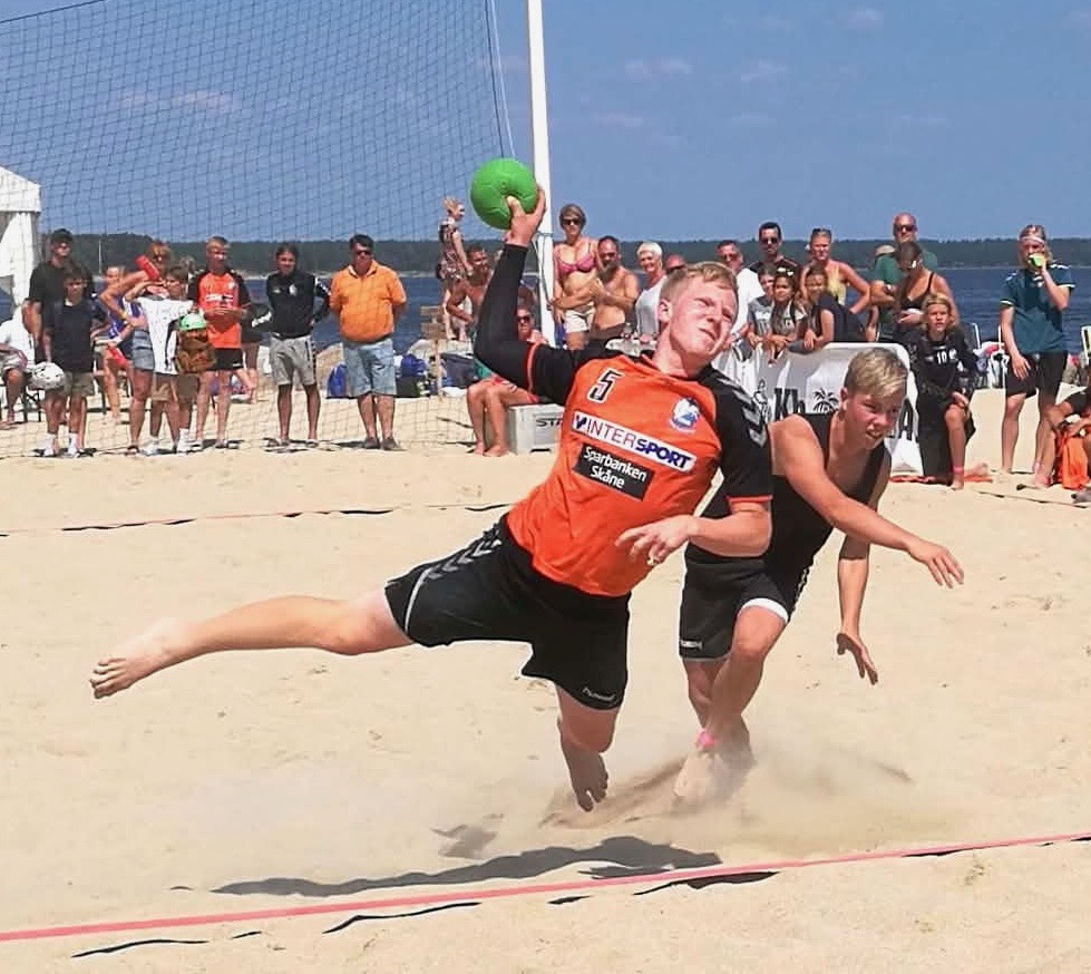 Emil Persson spelar beach-handboll på en strand.